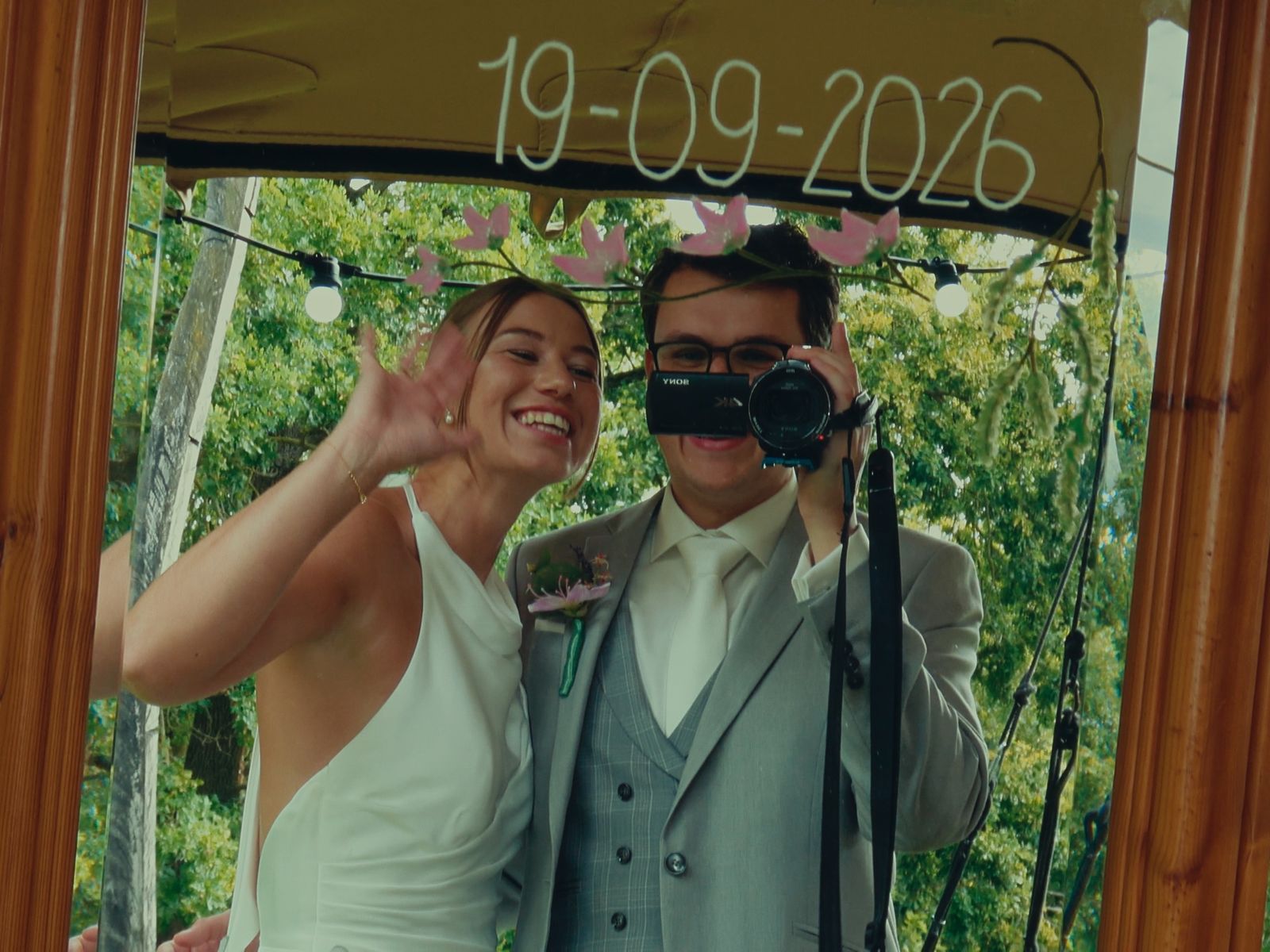 Bruidspaar filmt zichzelf met de camcorder in een spiegel, met hun trouwdatum erboven