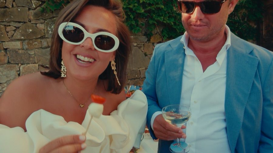 Scherpe still uit een POV-trouwfilm: gasten met zonnebril en champagne